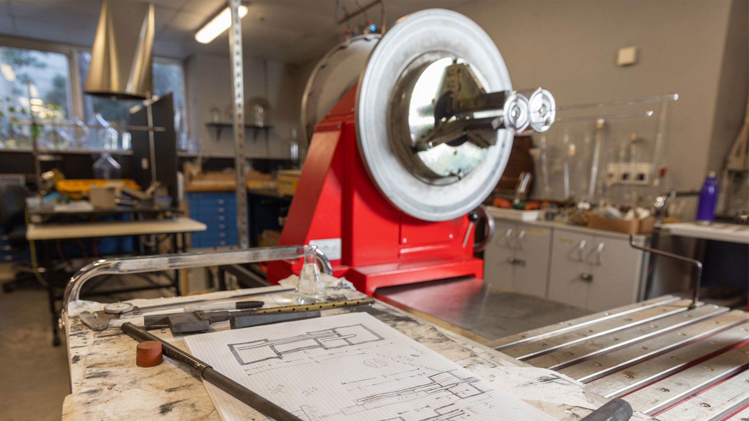 An image of sketches with glass blowing tools in the background.