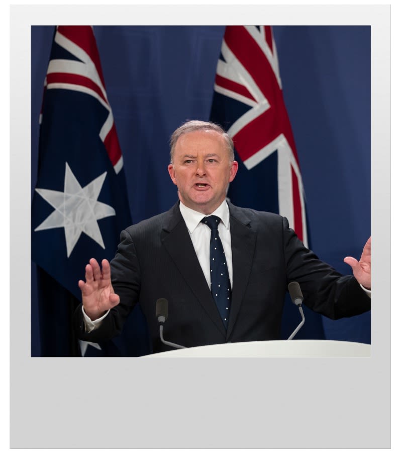 Leader of the Opposition Anthony Albanese standing on a podium in front of two Australian flags