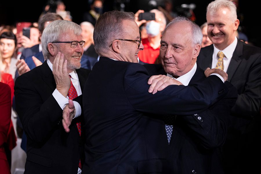Anthony Albanese and Paul Keating embrace each other, with Kevin Rudd smiling in the background.