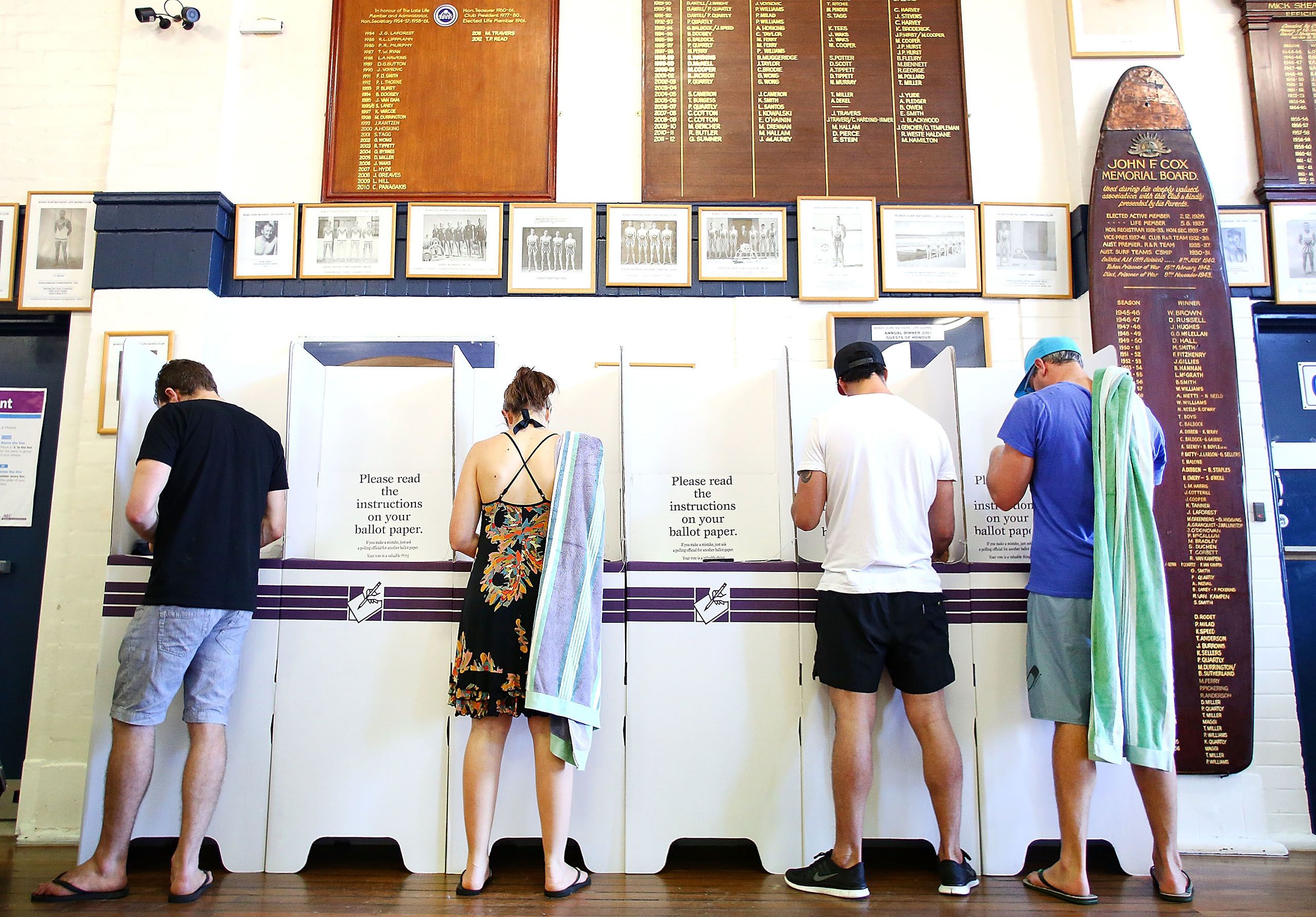 People voting at a ballot box in Bondi - some are carrying beach towels over their shoulders
