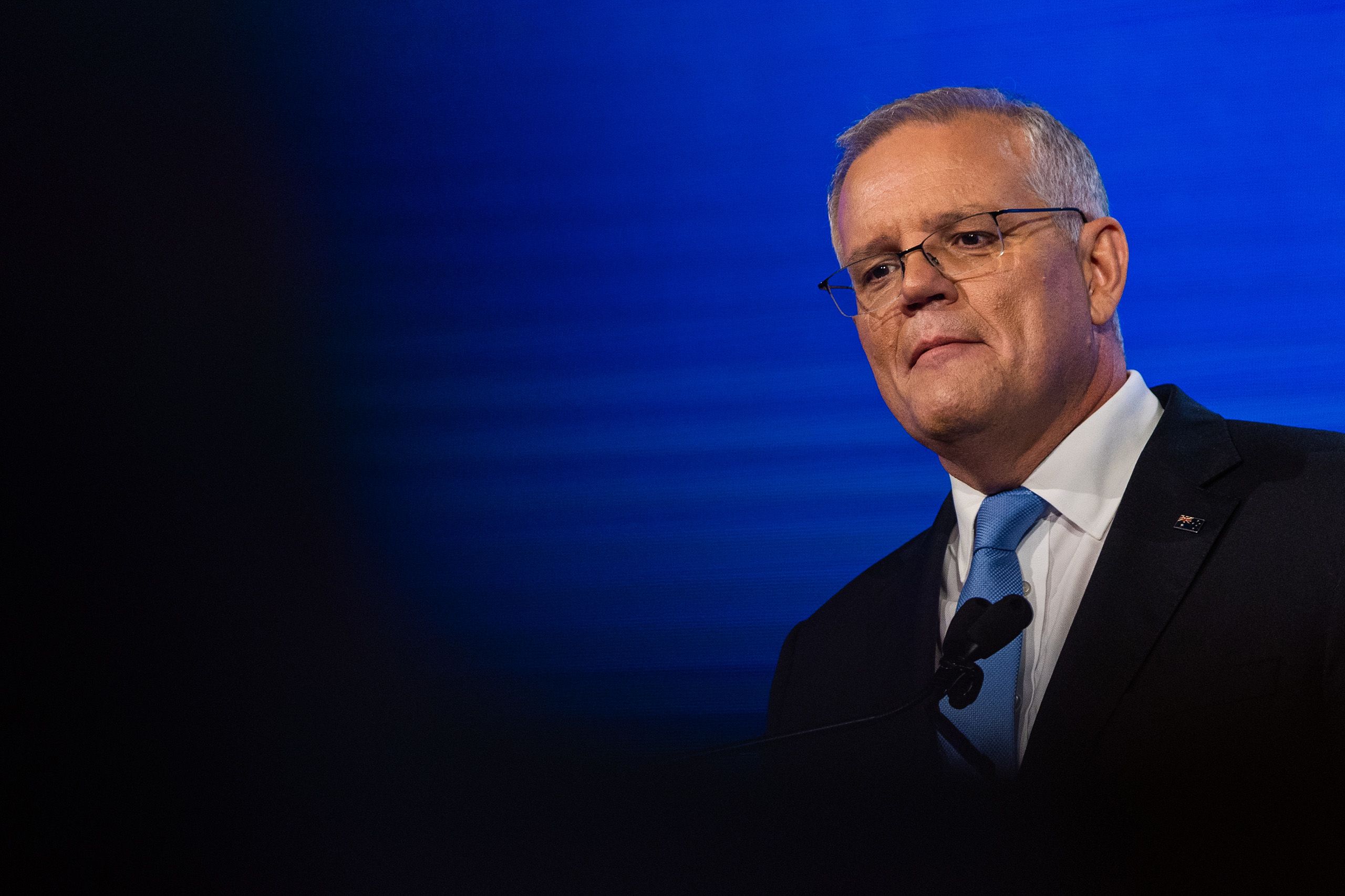 Prime Minister Scott Morrison standing in front of a blue background