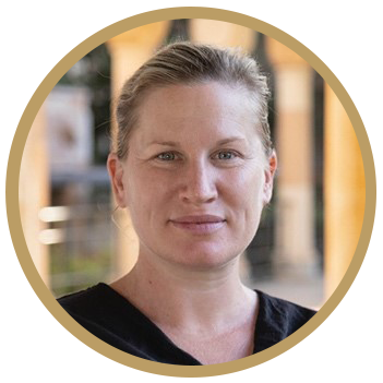 A circle portrain of a woman smiling into the camera. She has light eyes and blonde hair, she is wearing a black v-neck shirt.