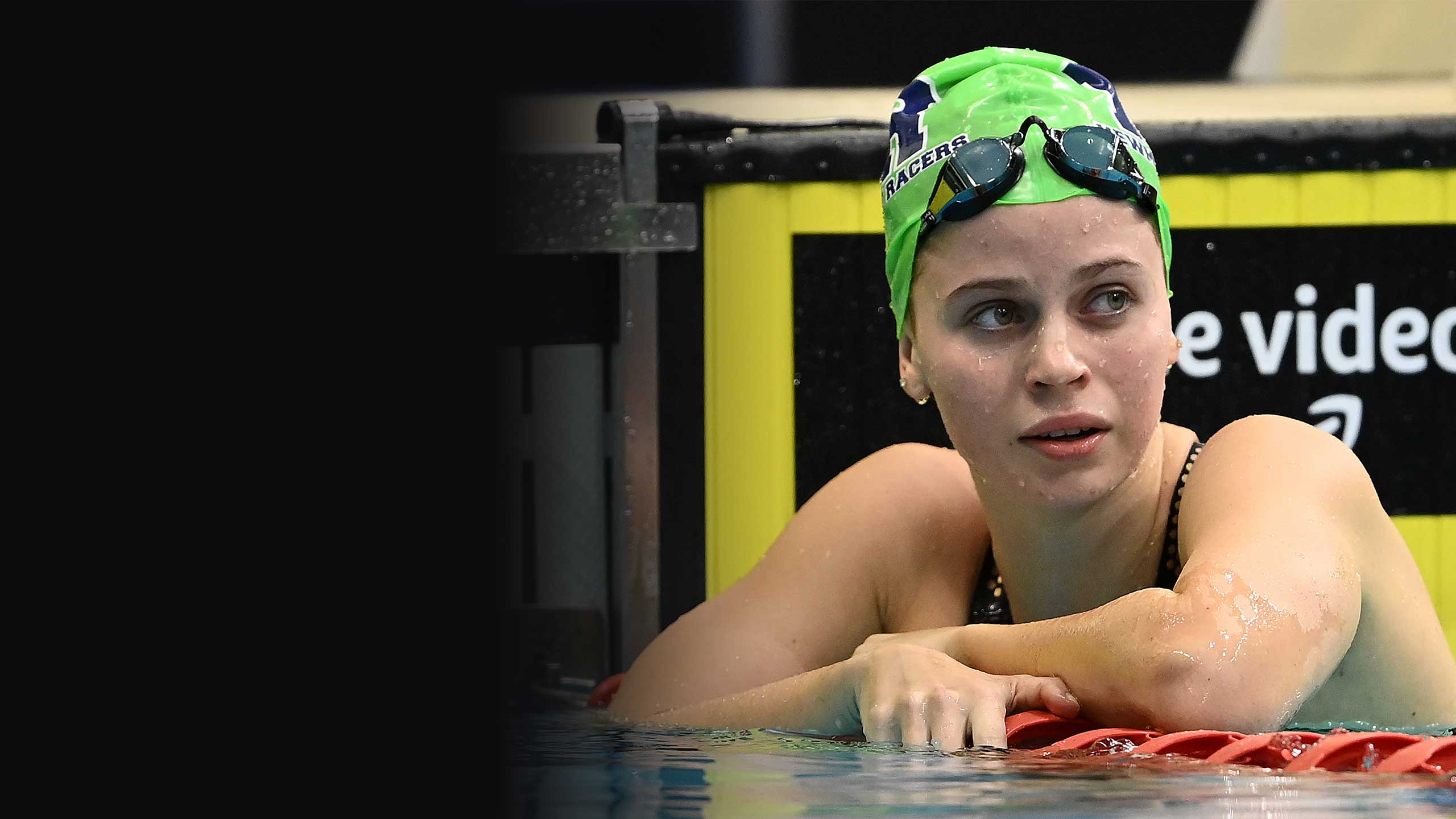An image UQ student Elizabeth Dekkers with her goggles on the top of her swimming cap and resting on a lane rope after a race.