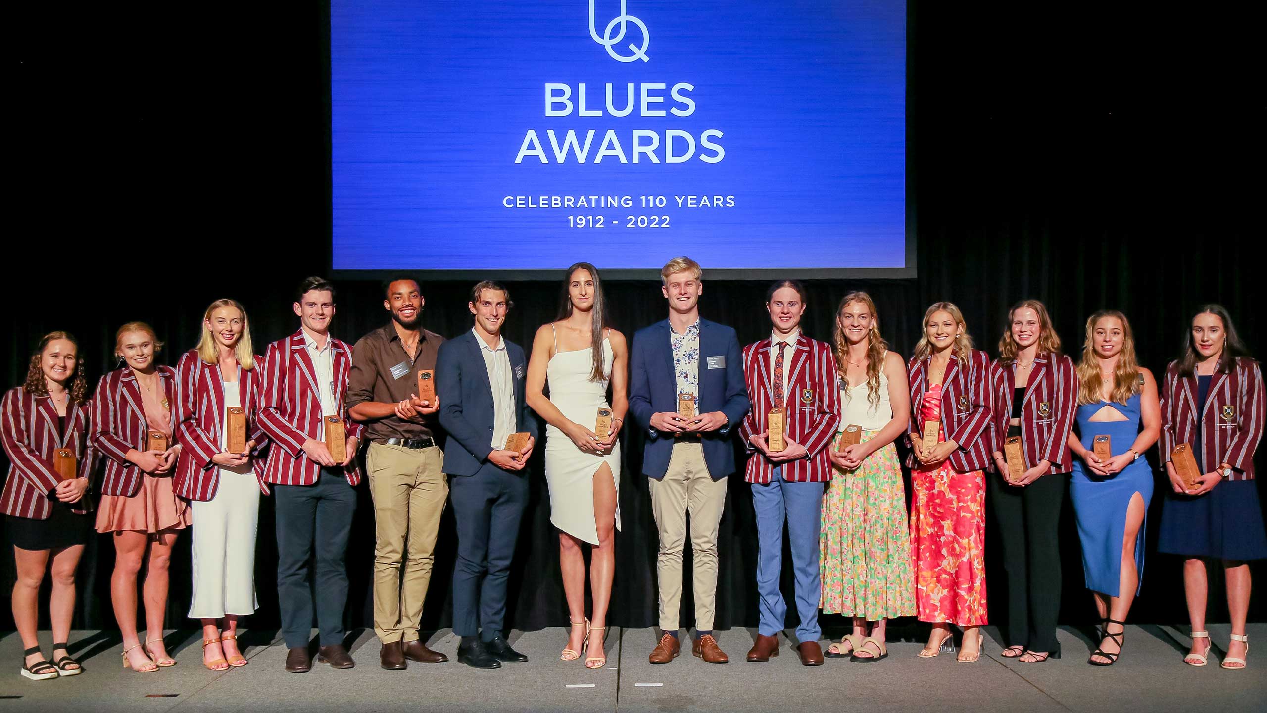 An image of The 2022 UQ Blue and Half Blue recipients on stage with their awards and blazers.
