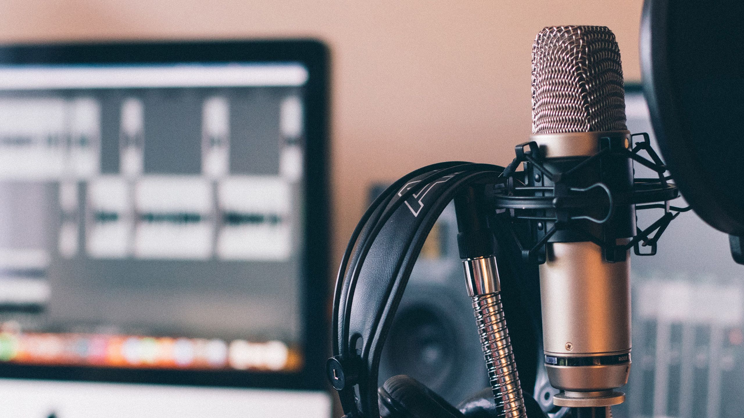 An image of a recording studio with a microphone and headphones in the foreground.
