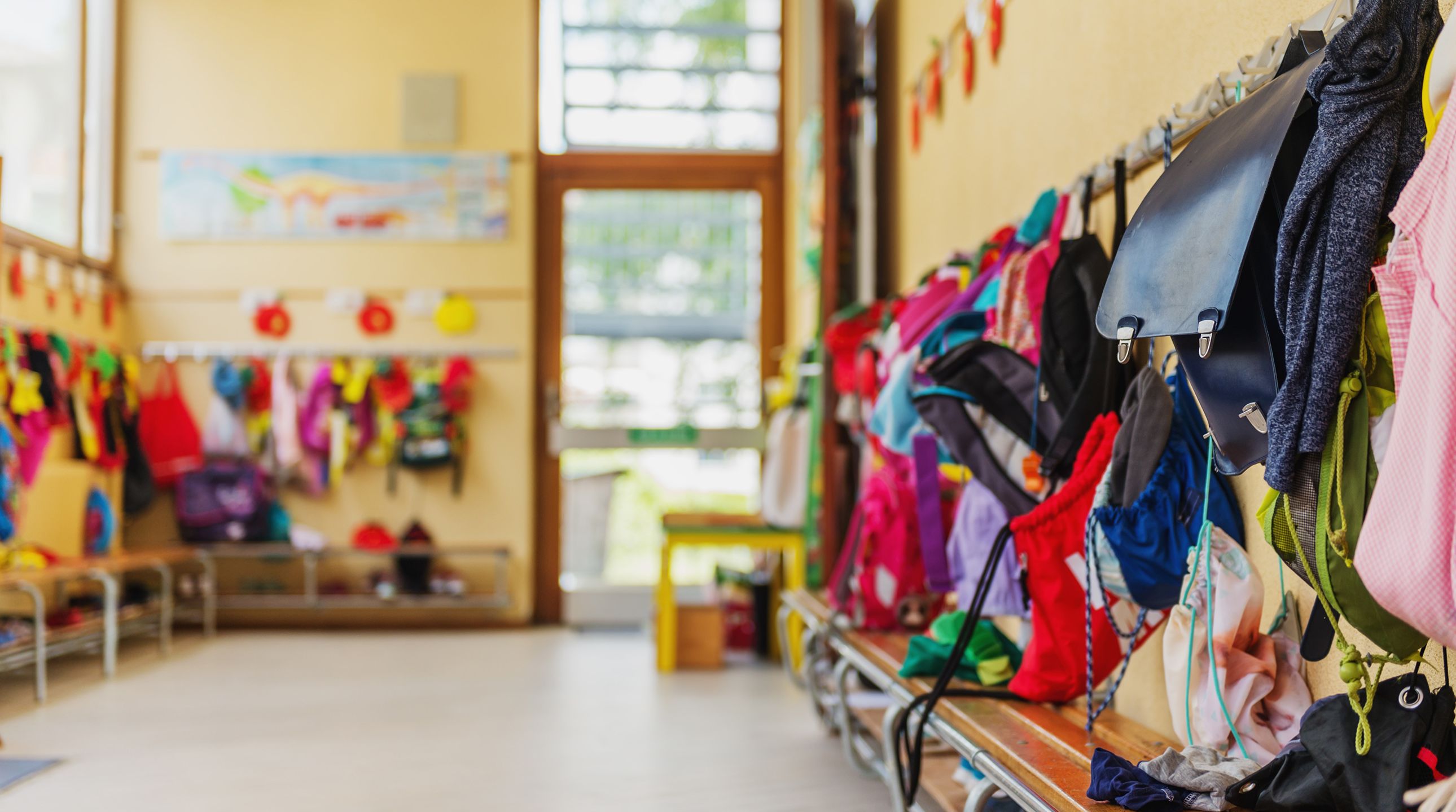 Empty hallway in the school, backpacks and bags on hooks, bright recreation room