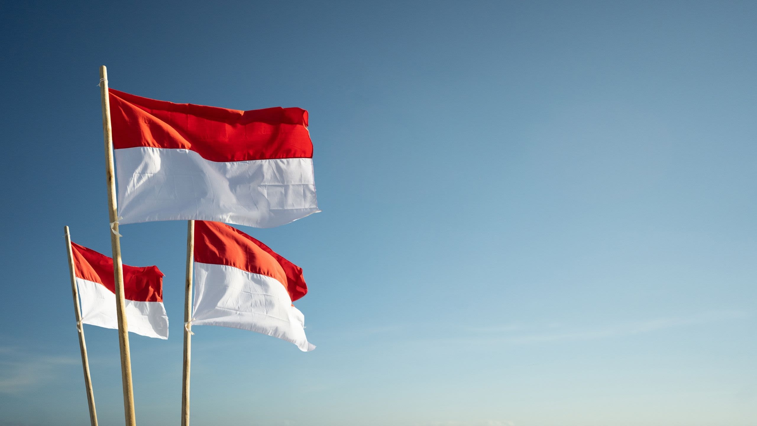 Three Indonesian flags flying from flagpoles.