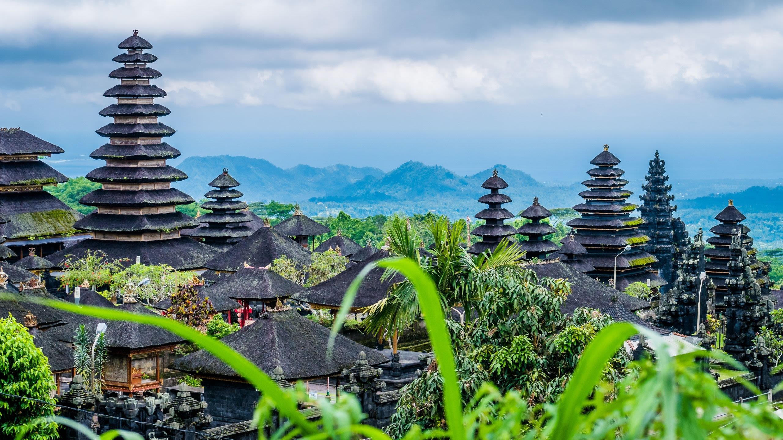 Traditional temple roofs soar high in green Balinese landscape.