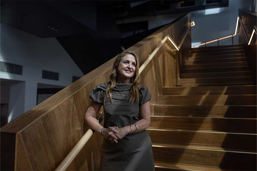 An image of HOTA Director of Operations and Transformations Anna Carroll standing on the stairs inside the HOTA gallery.