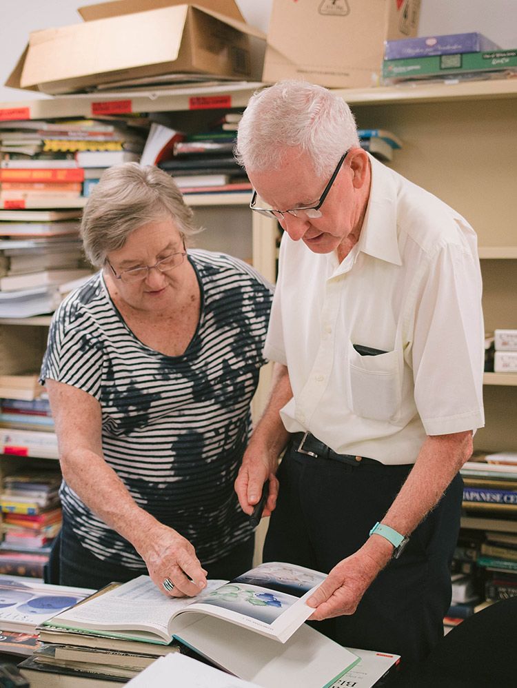 Two people looking at a table filled with books.