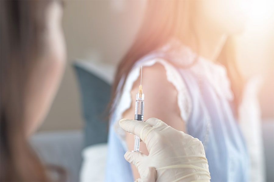 An image of a doctor about to inject a female patient with the HPV vaccine.