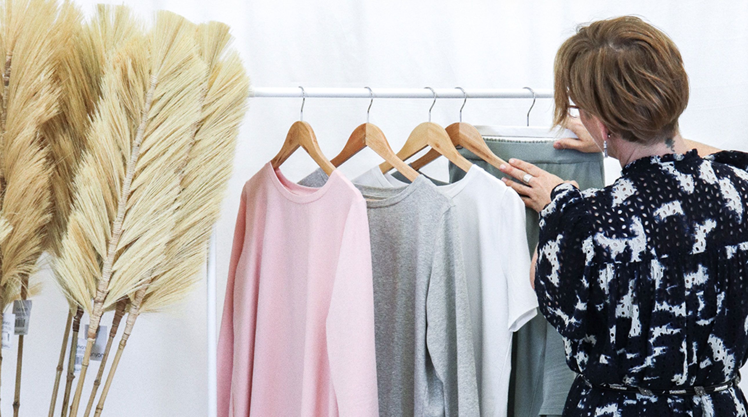 A rack of t-shirts in pink, grey and white colours.