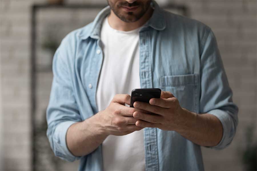 An image of a man scrolling on his mobile phone.