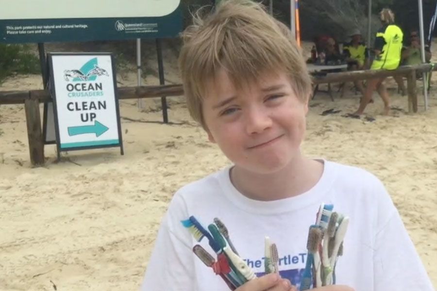 An image of Ned Heaton displaying the shocking amount of plastic toothbrushes washed on the ocean during a beach clean-up in the Moreton Bay National Park.