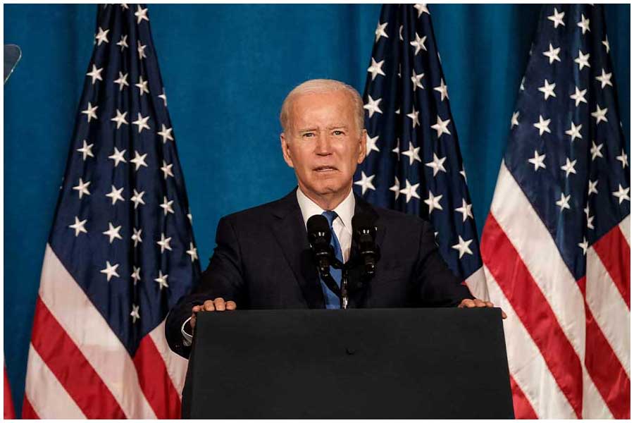 An image of US President Joe Biden, standing on a podium in front of American flags, addressing the media ahead of the midterm elections