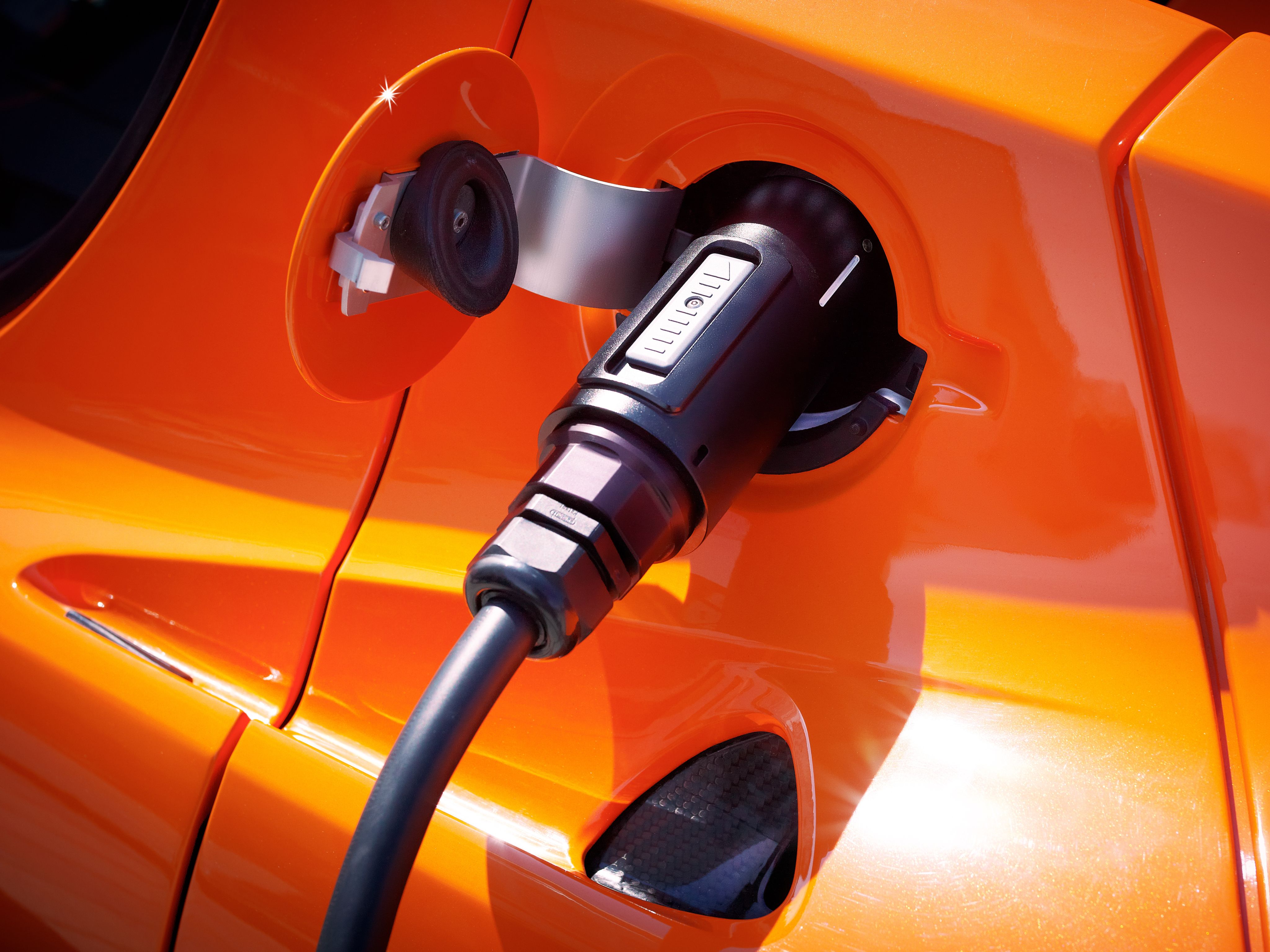 Close-up of a charger plugged into an orange electric car