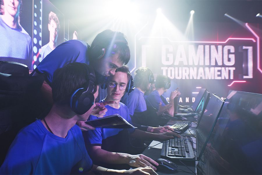 Esportsman gamer in headsets listening to trainer explaining game strategy at the start of a professional esports competition.