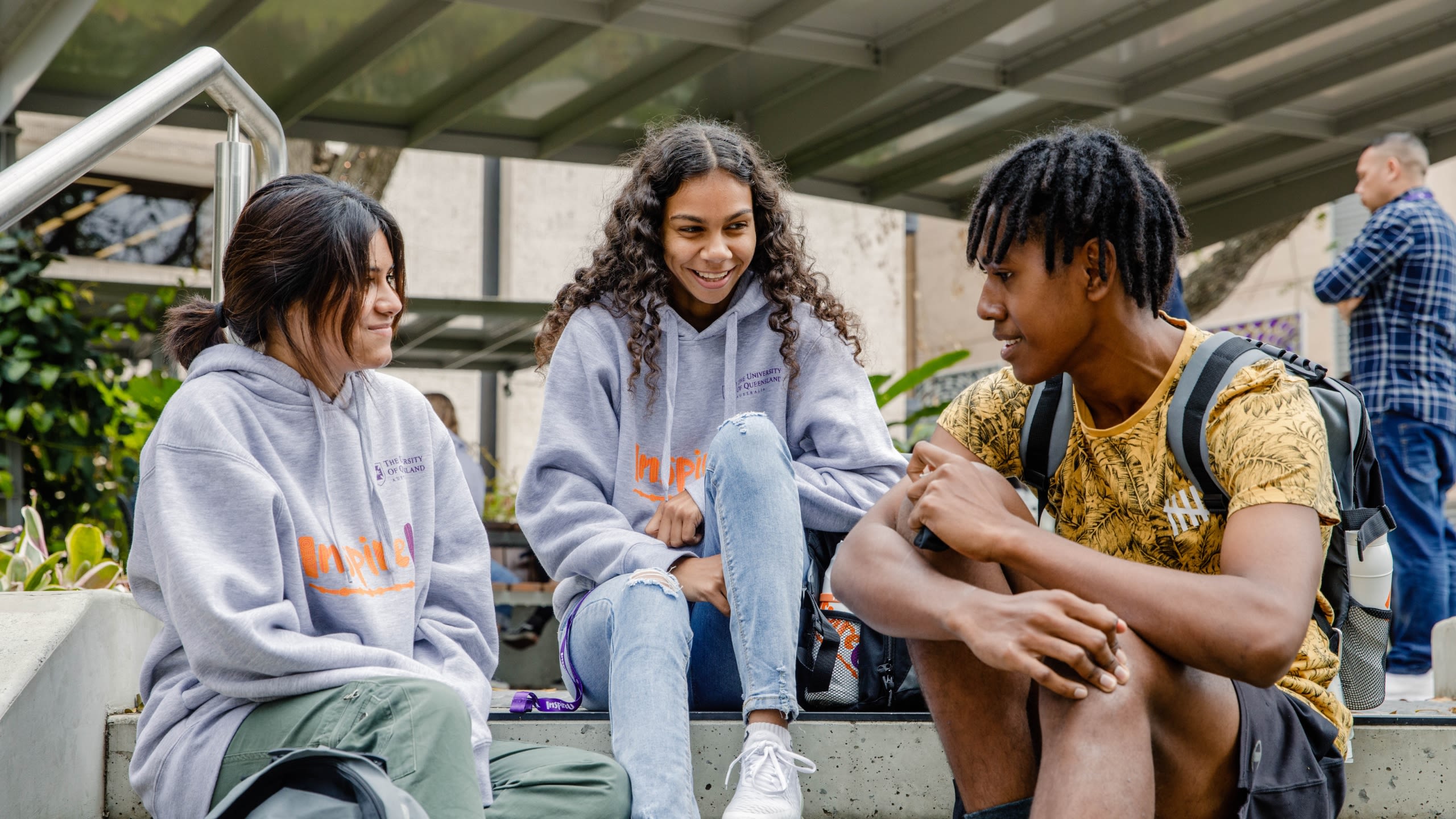 Three students sit together talking and smiling