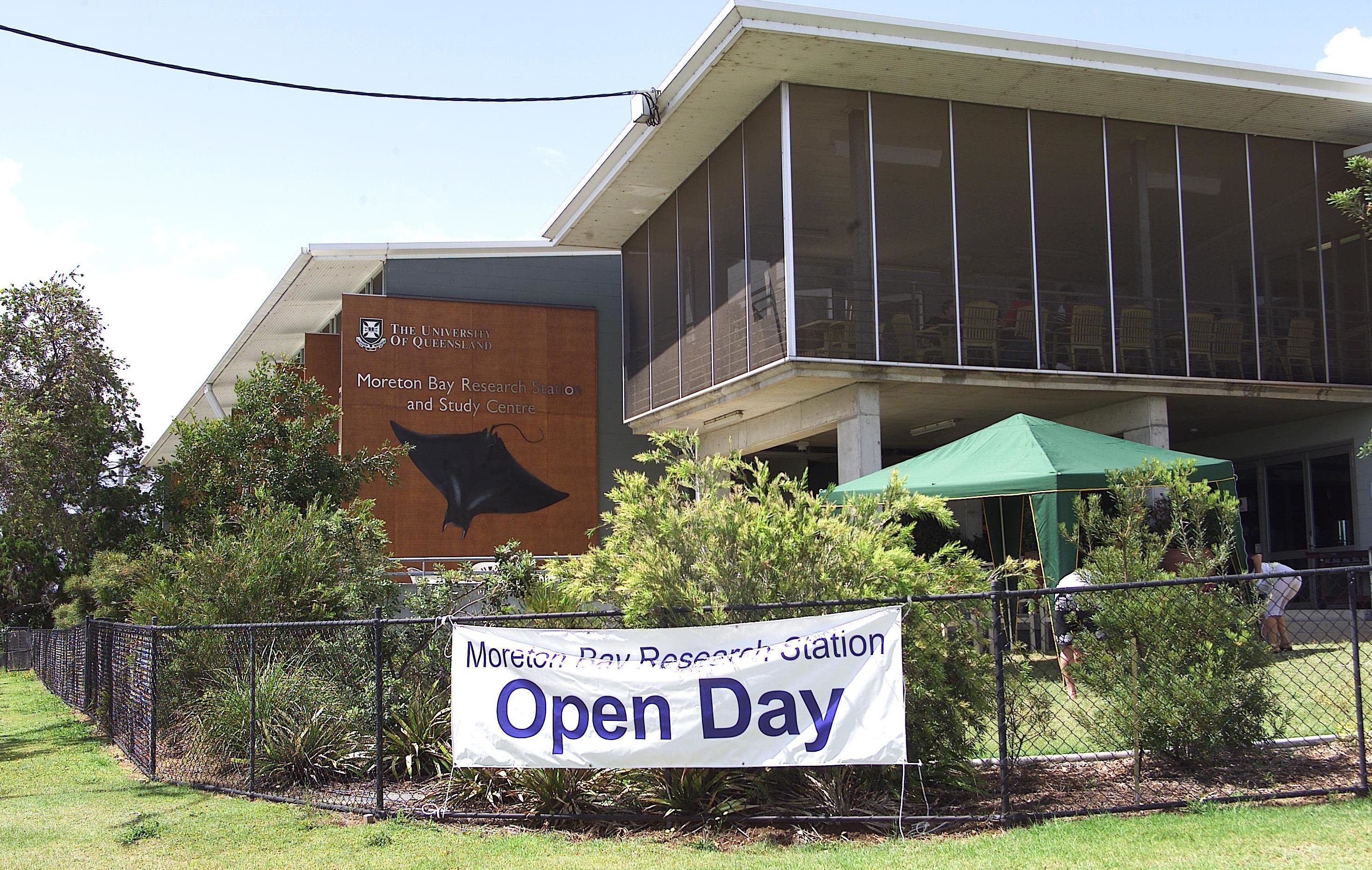 A large research building with an Open Day banner hanging on the fence. There is a large stingray motif on the building wall.