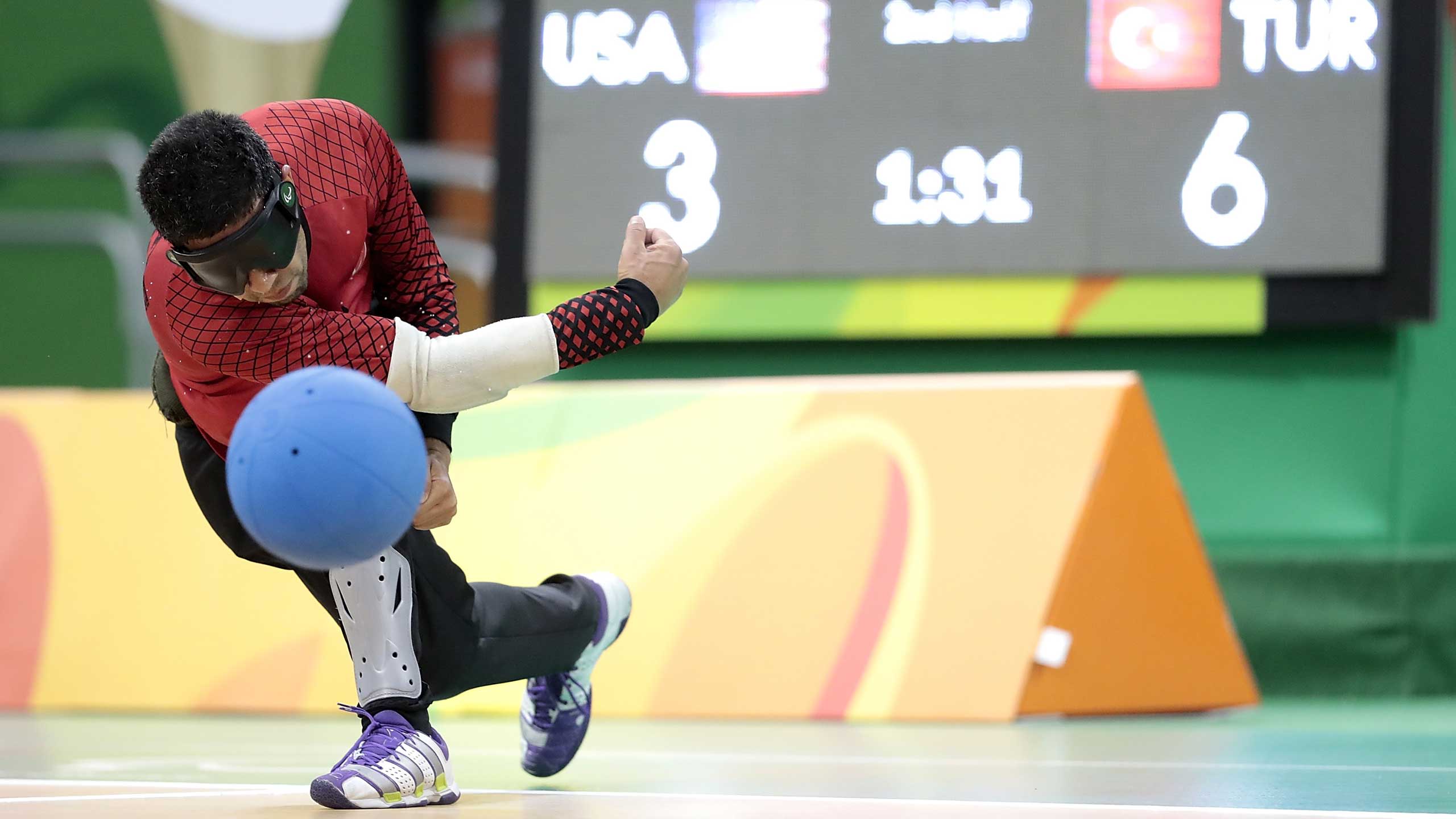 A goalball player launches a ball at the net.