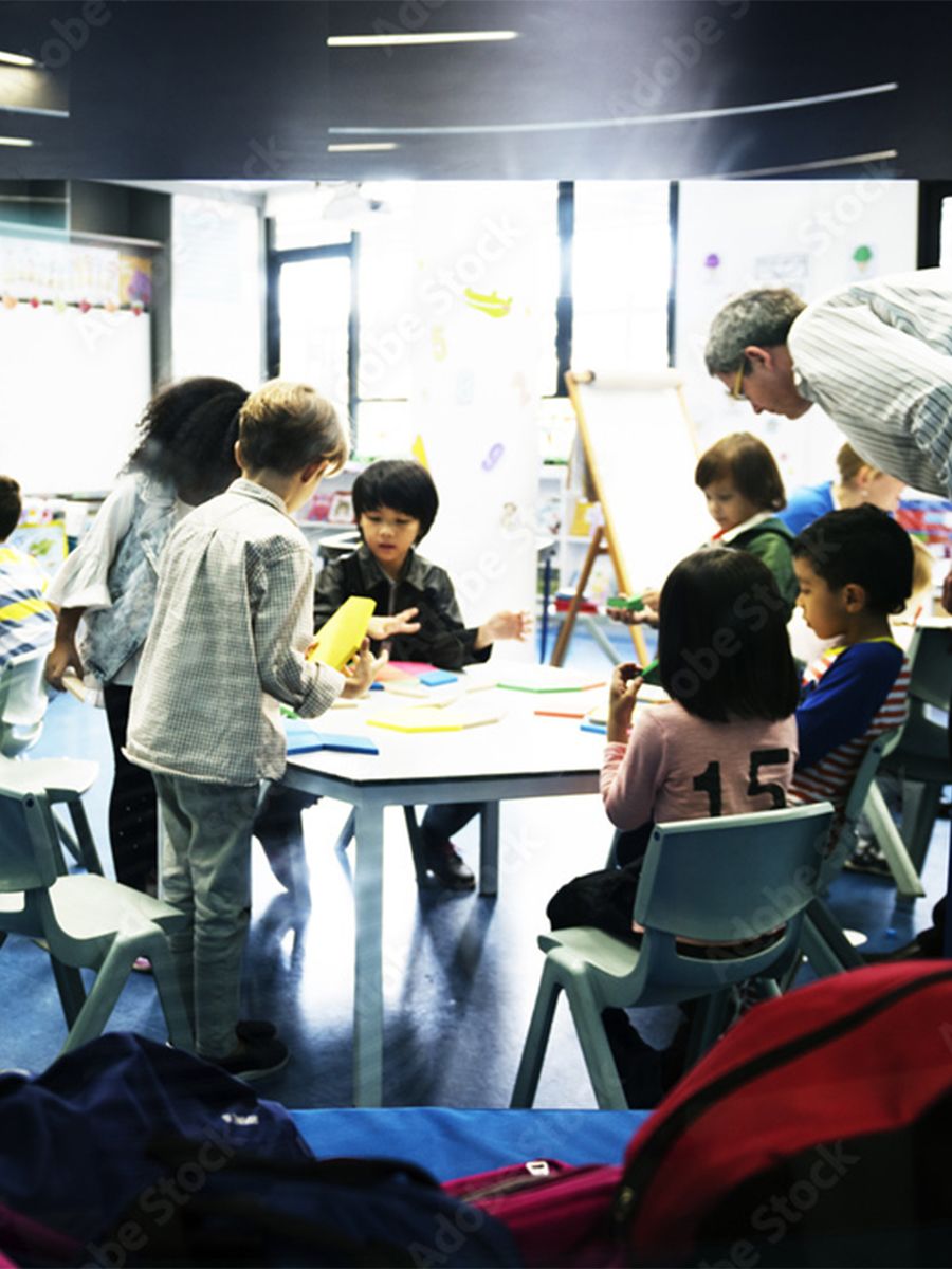 An image of a group of children sitting and crafting around a shared table at after school care.