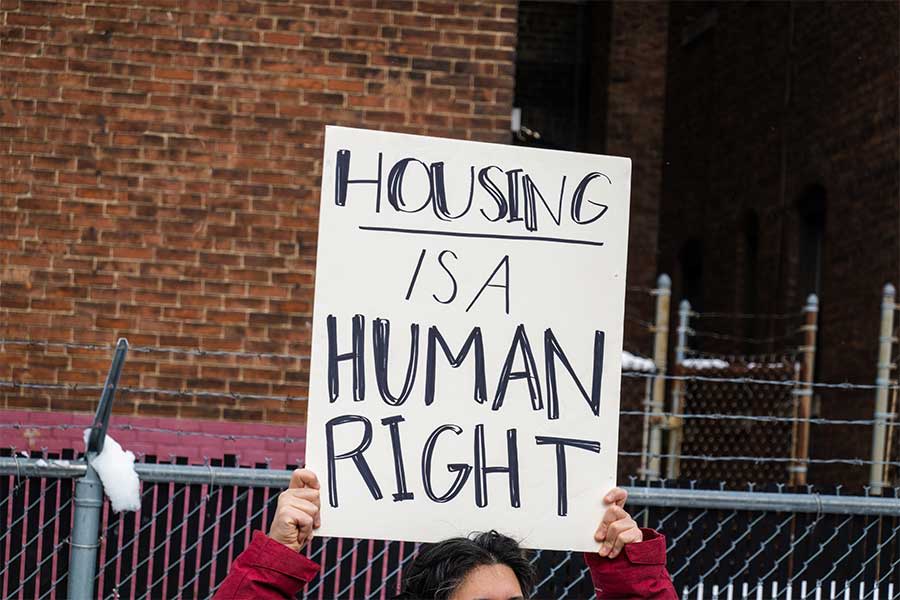 An image of a man holding a sign, which reads: Housing is a human right.