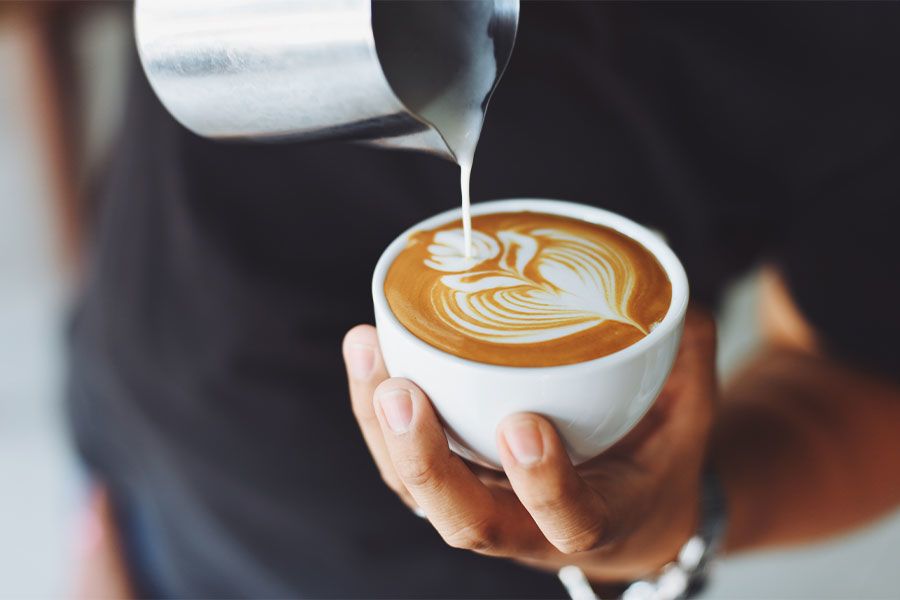 A barista pours milk into a coffee cup.
