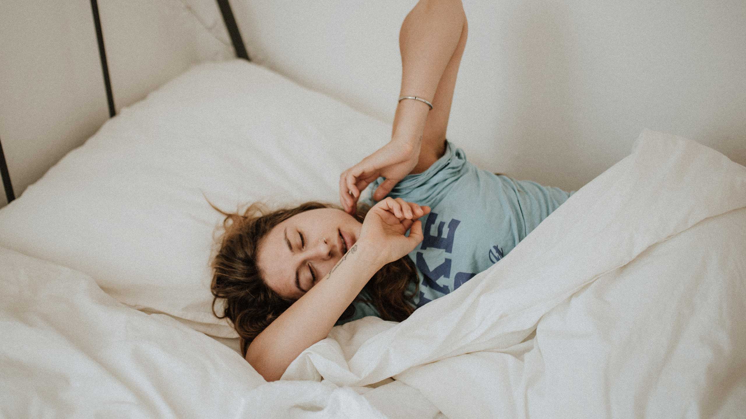 Woman stretching in bed after waking up in the morning.