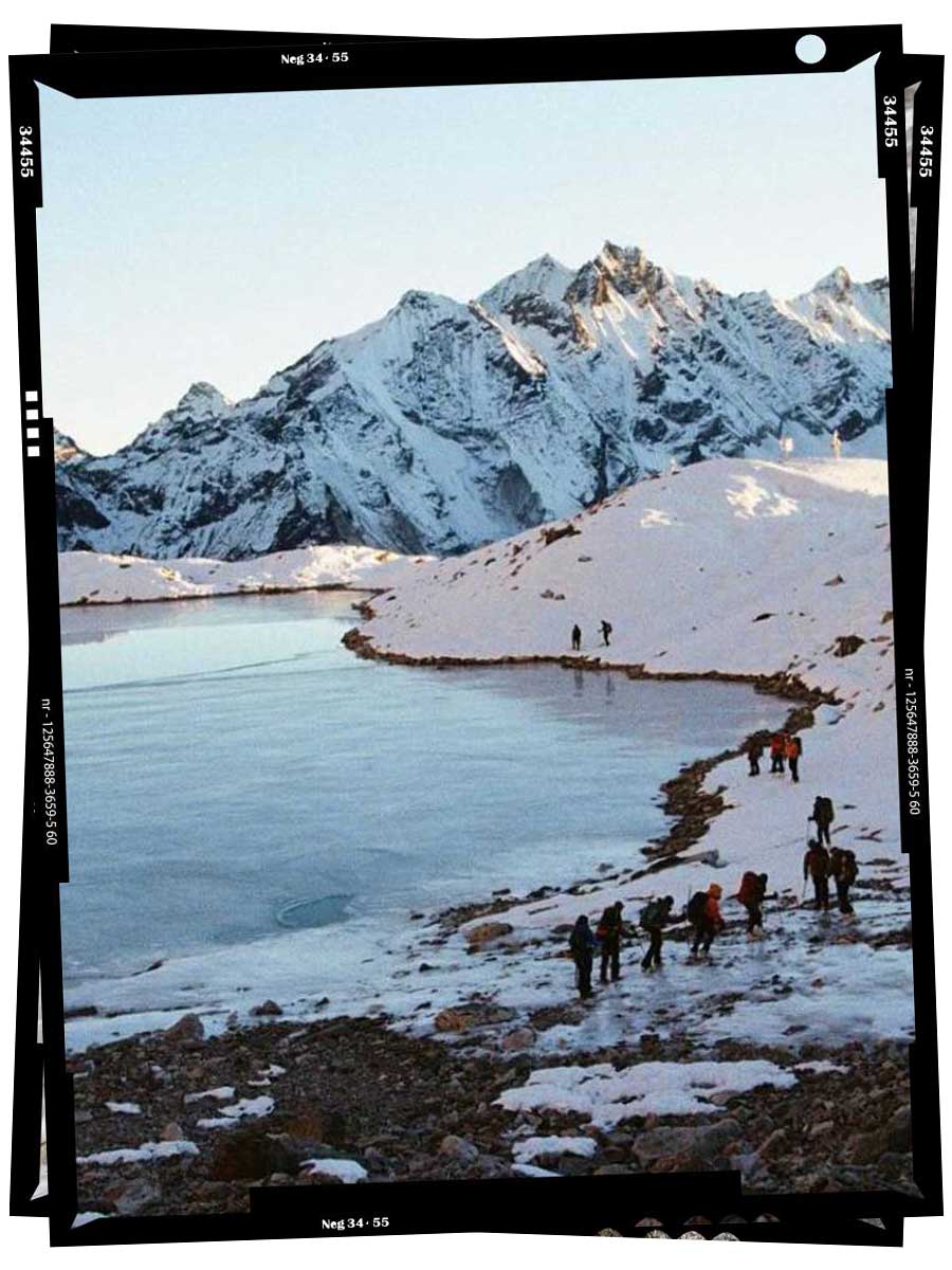 An image of hikers walking past an icy lake during their summit of Tsorku Peak.