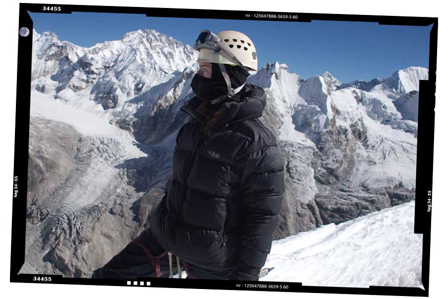 An image of UQ student Emerald Gaydon standing in front of snow-covered mountains and a clear blue sky during her summit of Tsorku Peak in the Himalayas.