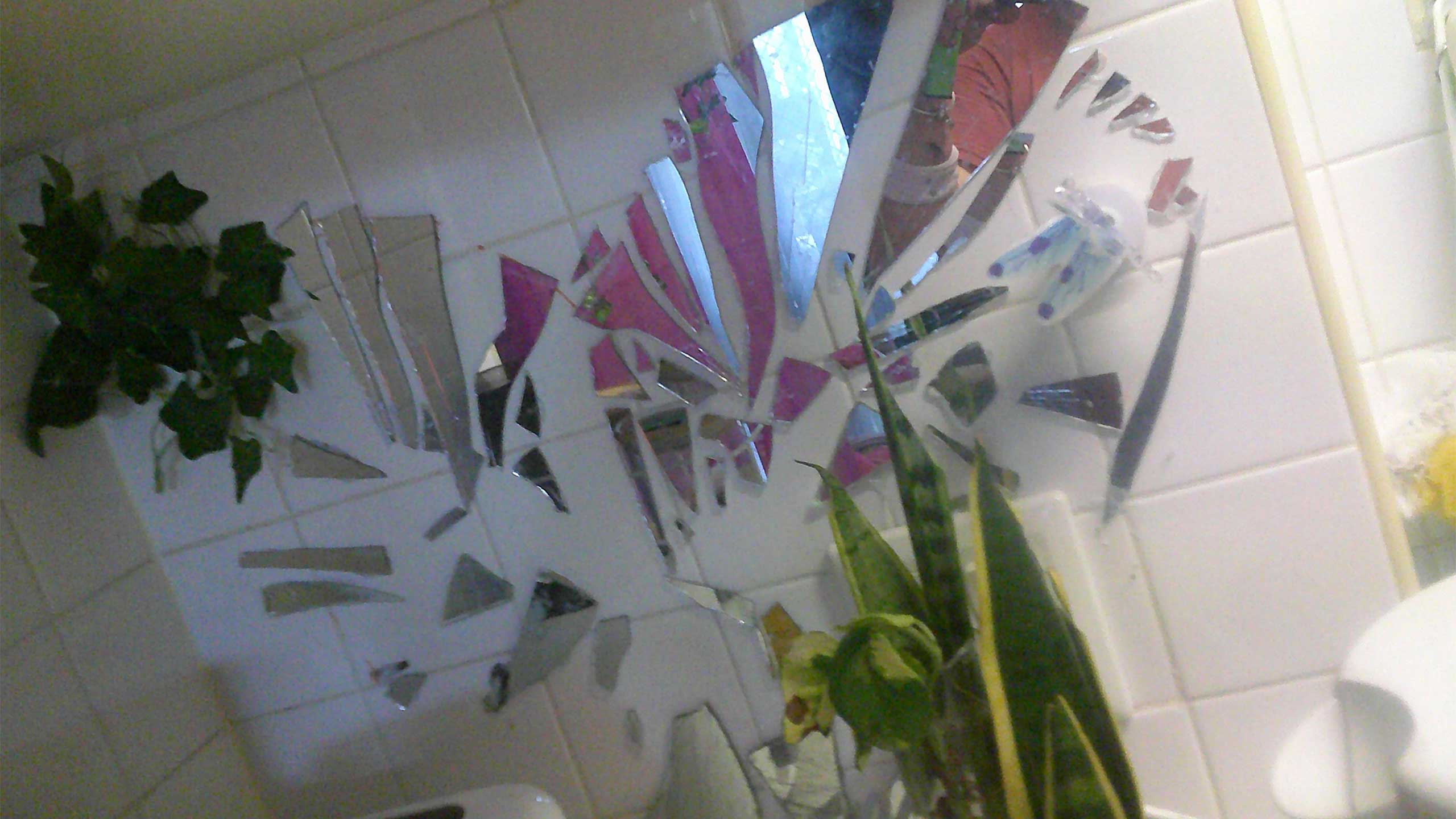 Broken mirror in shape of a heart on tiled wall