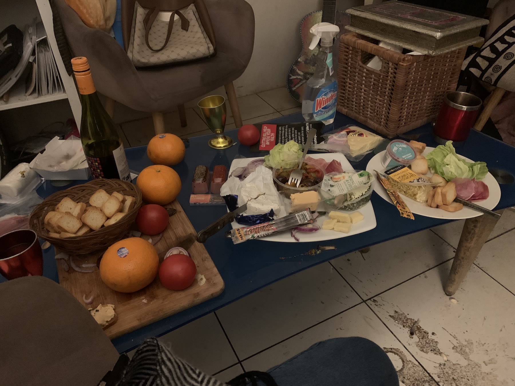 A coffee-table with several plates of food on top.