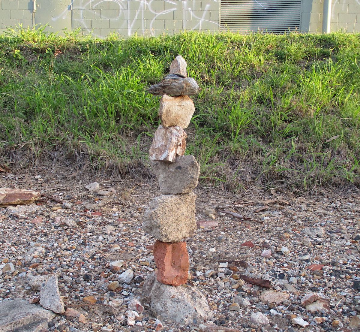 Several rocks piled vertically on stony ground.