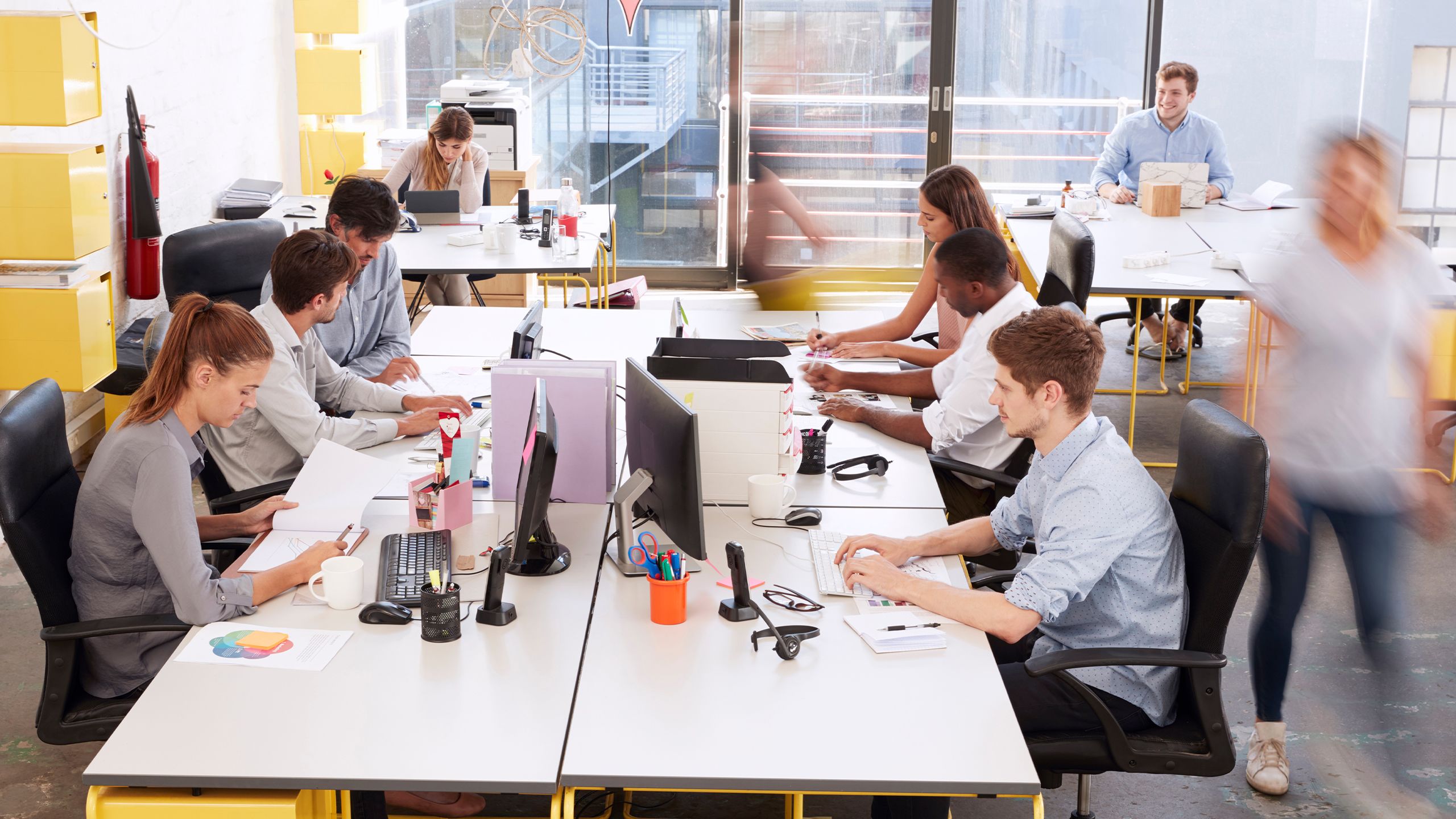 Staff walking through a busy open plan office.