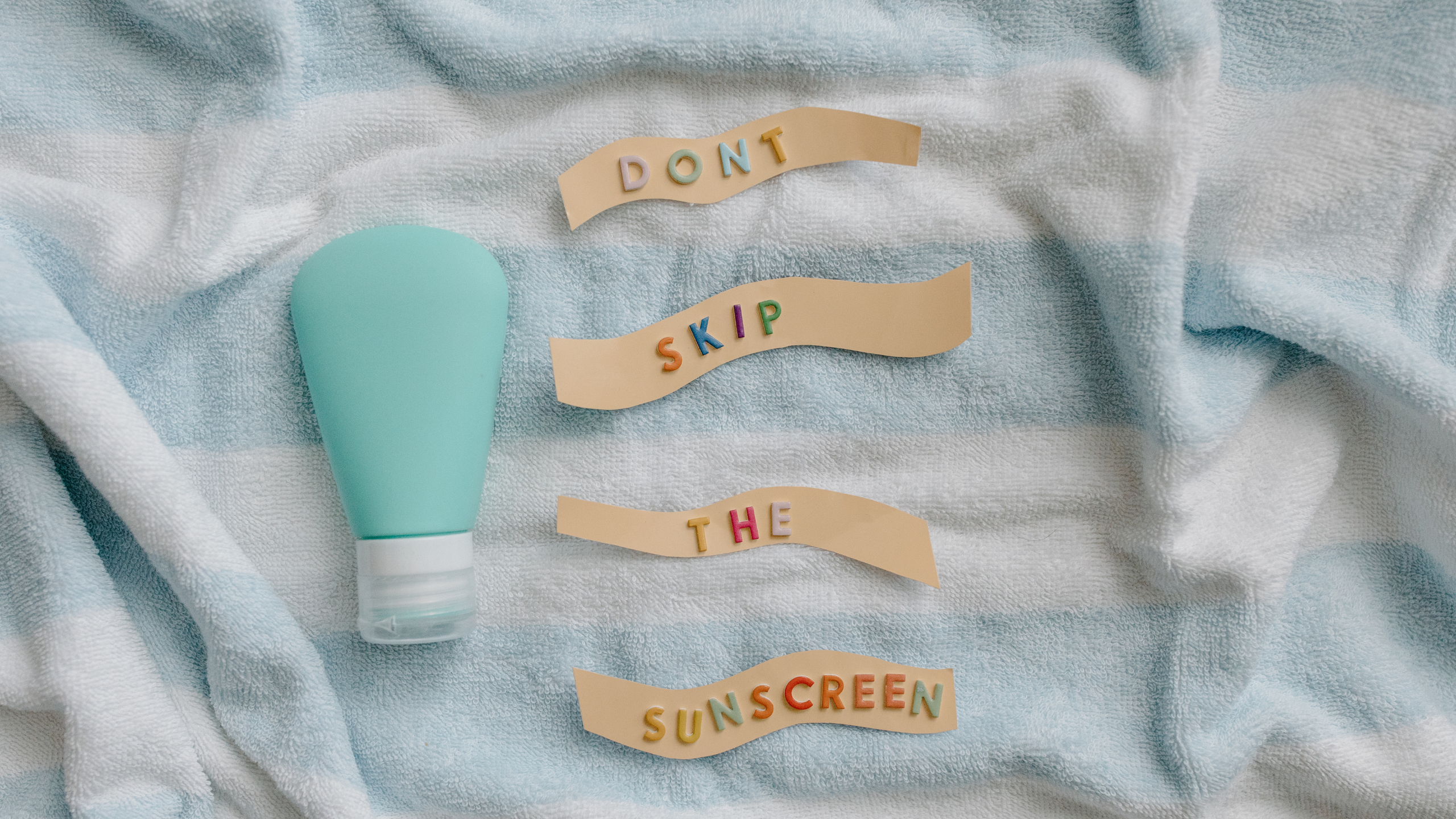 Sunscreen tube on blue and white striped towel