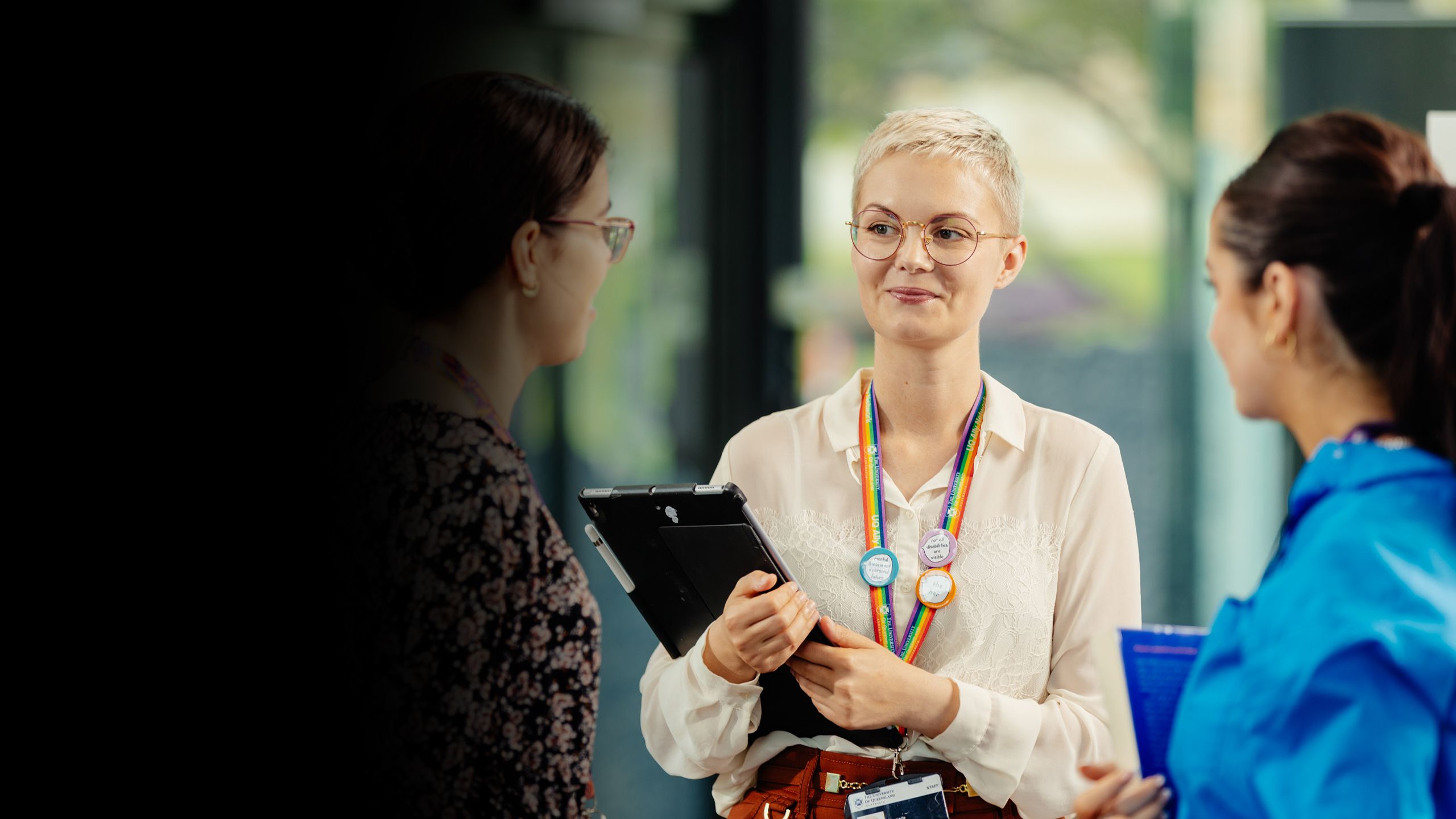 An image of Danielle Harvey holding and iPad and talking to colleagues.