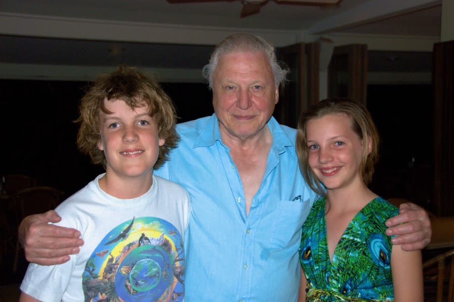 Bernard and Sandie's two pre-teenage children standing with David Attenborough, who has his arms around each child's shoulders