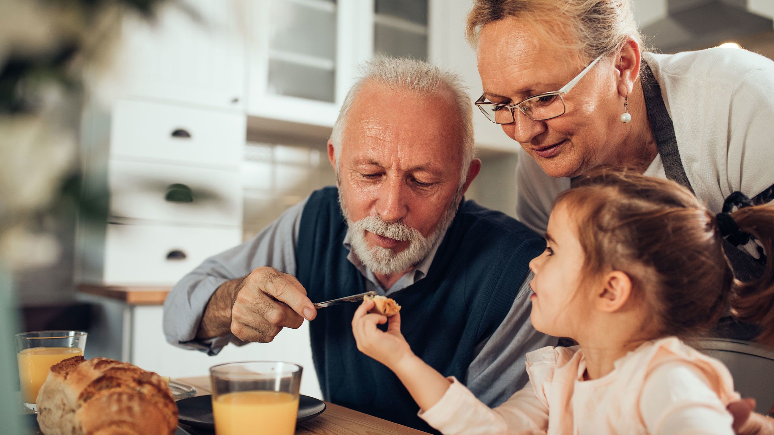 Grandparents making breakfast with their granddaughter.