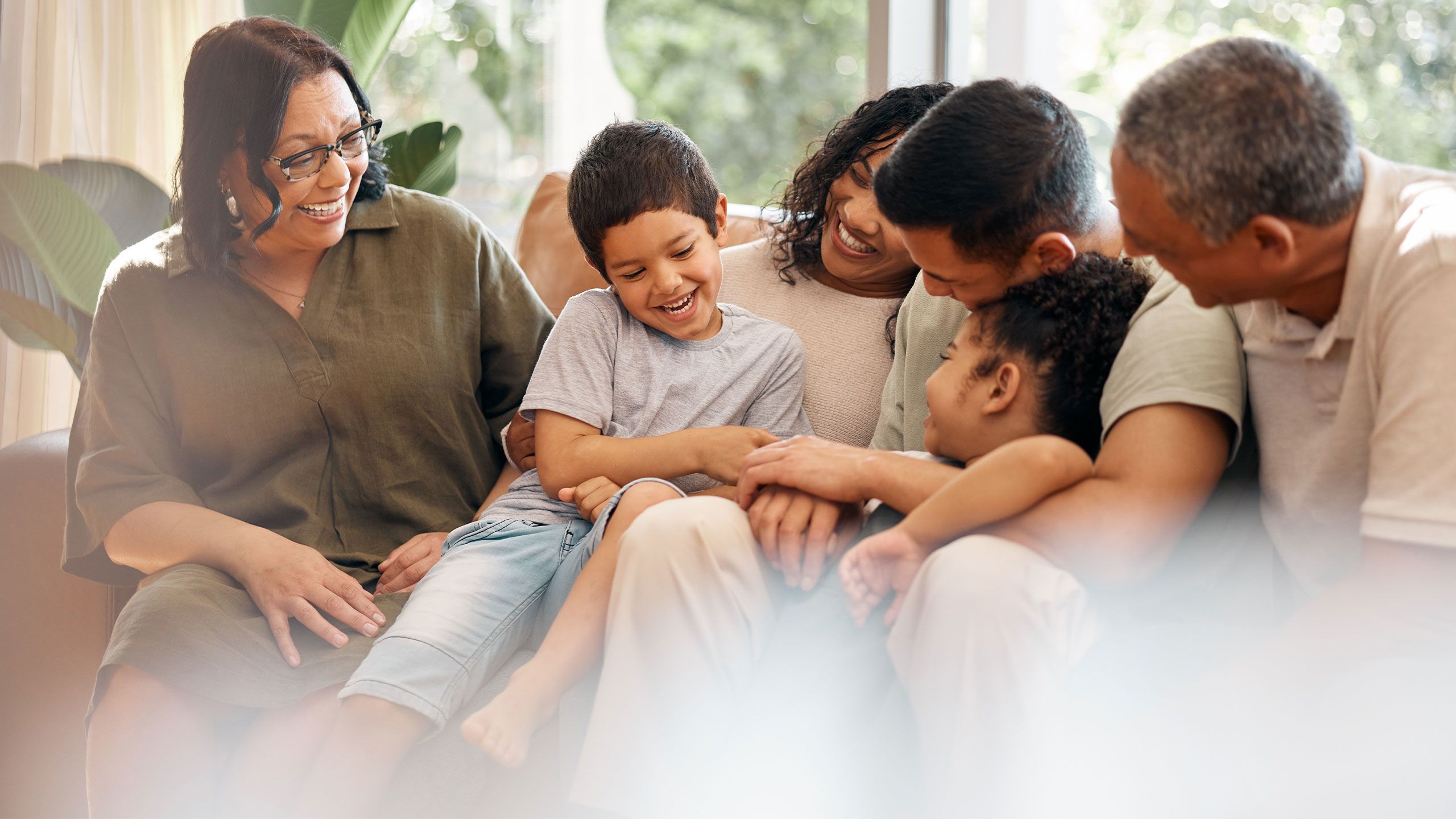 Parents and grandparents interacting together with children on a couch.