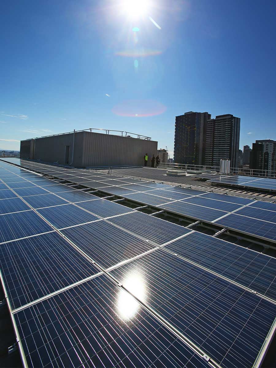 The sun reflects from solar panels on the rooftop of a building.