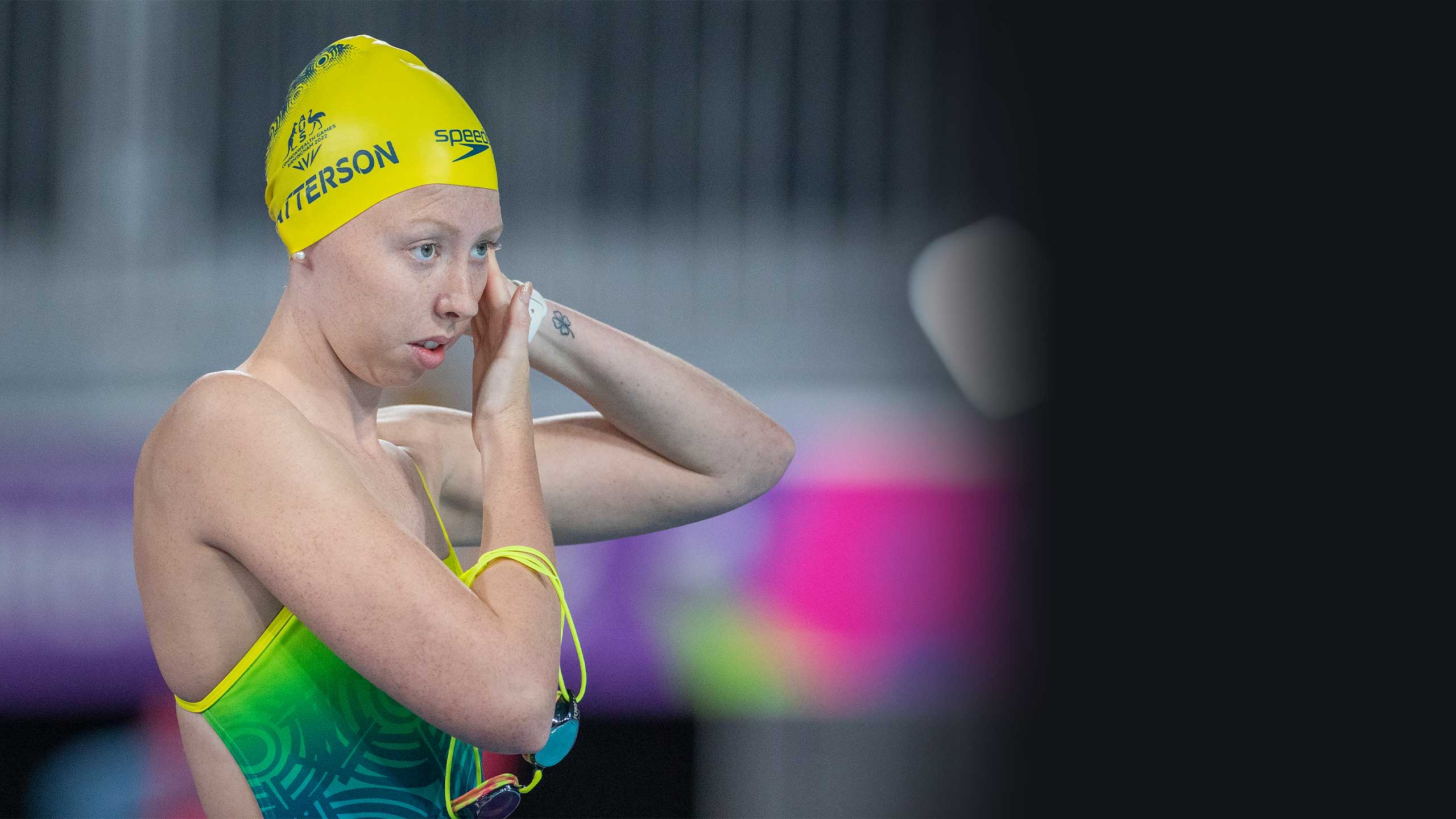 An image of UQ student and Paralympian Lakeisha Patterson putting on her swimming cap at the starting blocks during the 2022 Commonwealth Games.