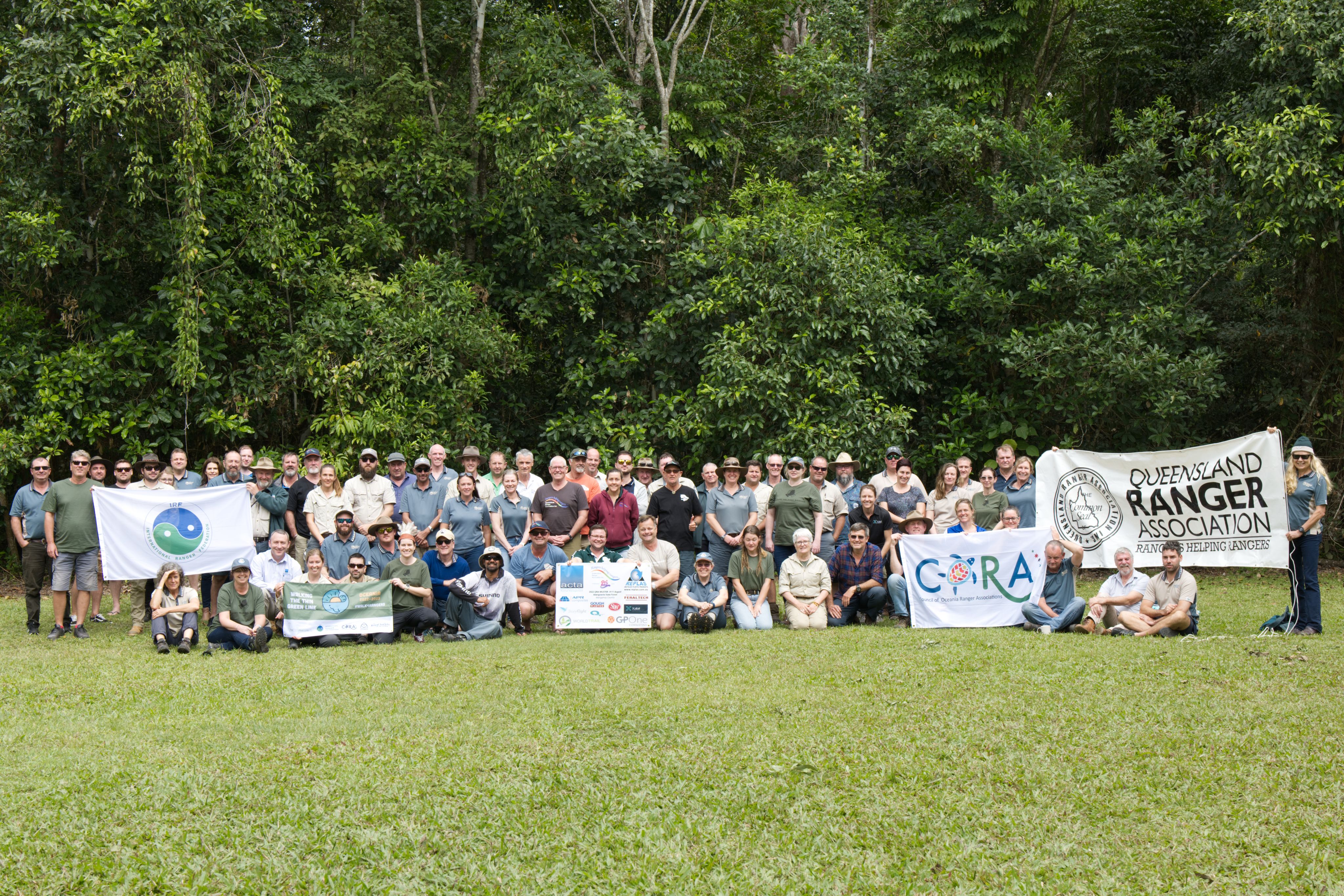 A group of 67 people holding ranger banners sitting on the grass