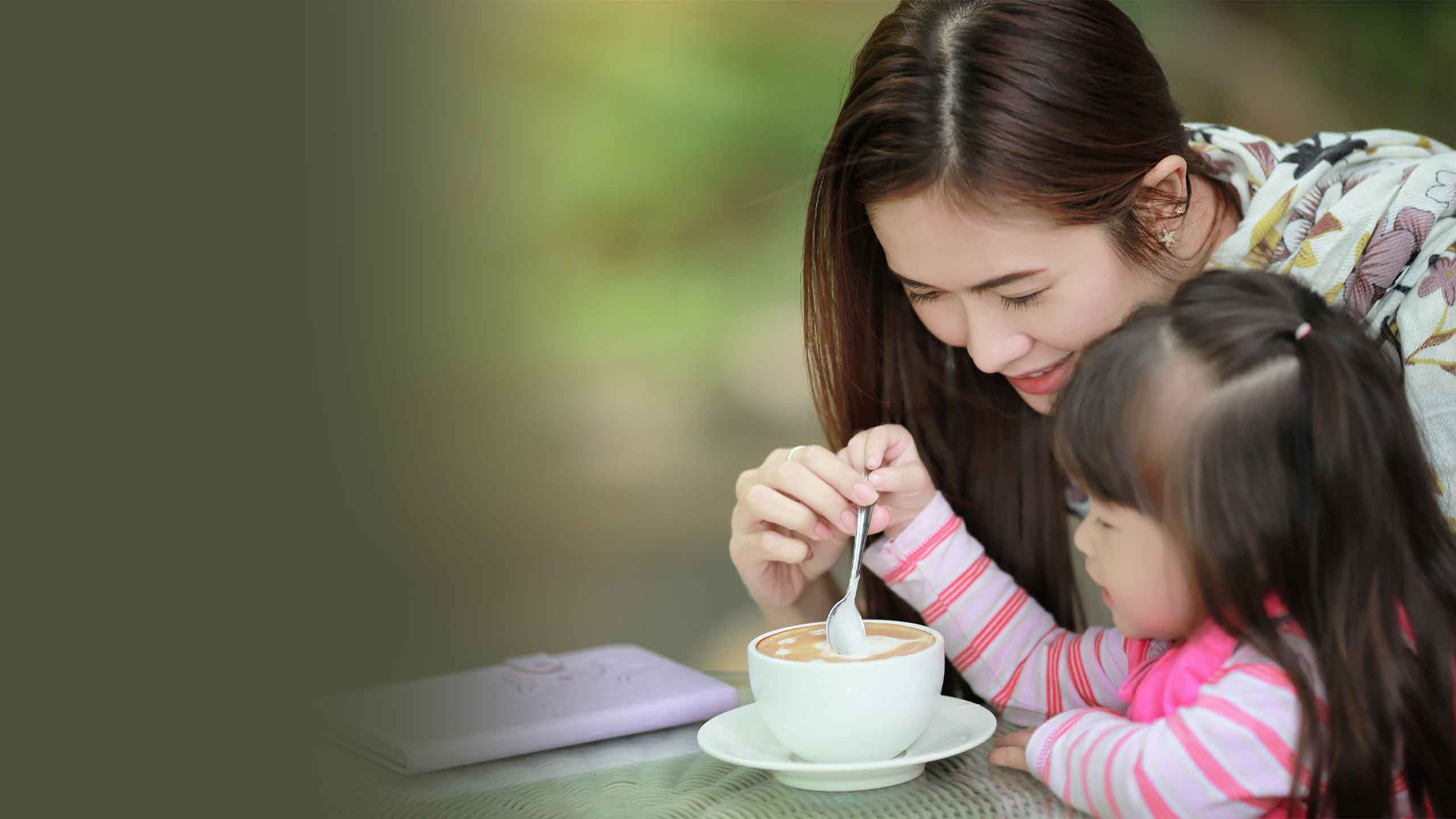 Young mother having a coffee and relaxing together with her young daughter.