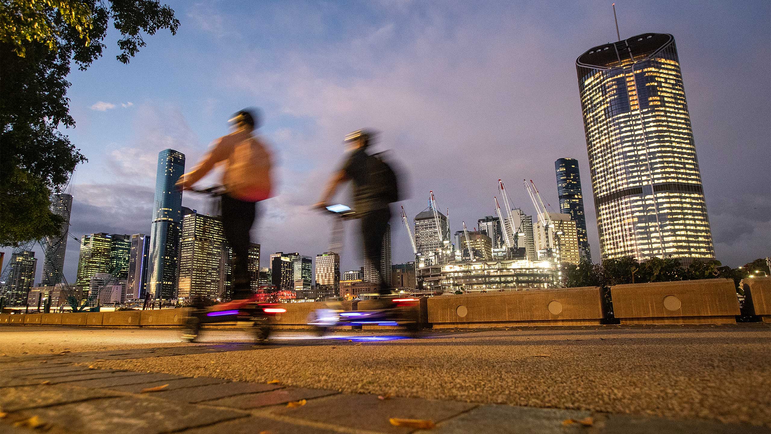 People ride scooters in the evening along Southbank in Brisbane.