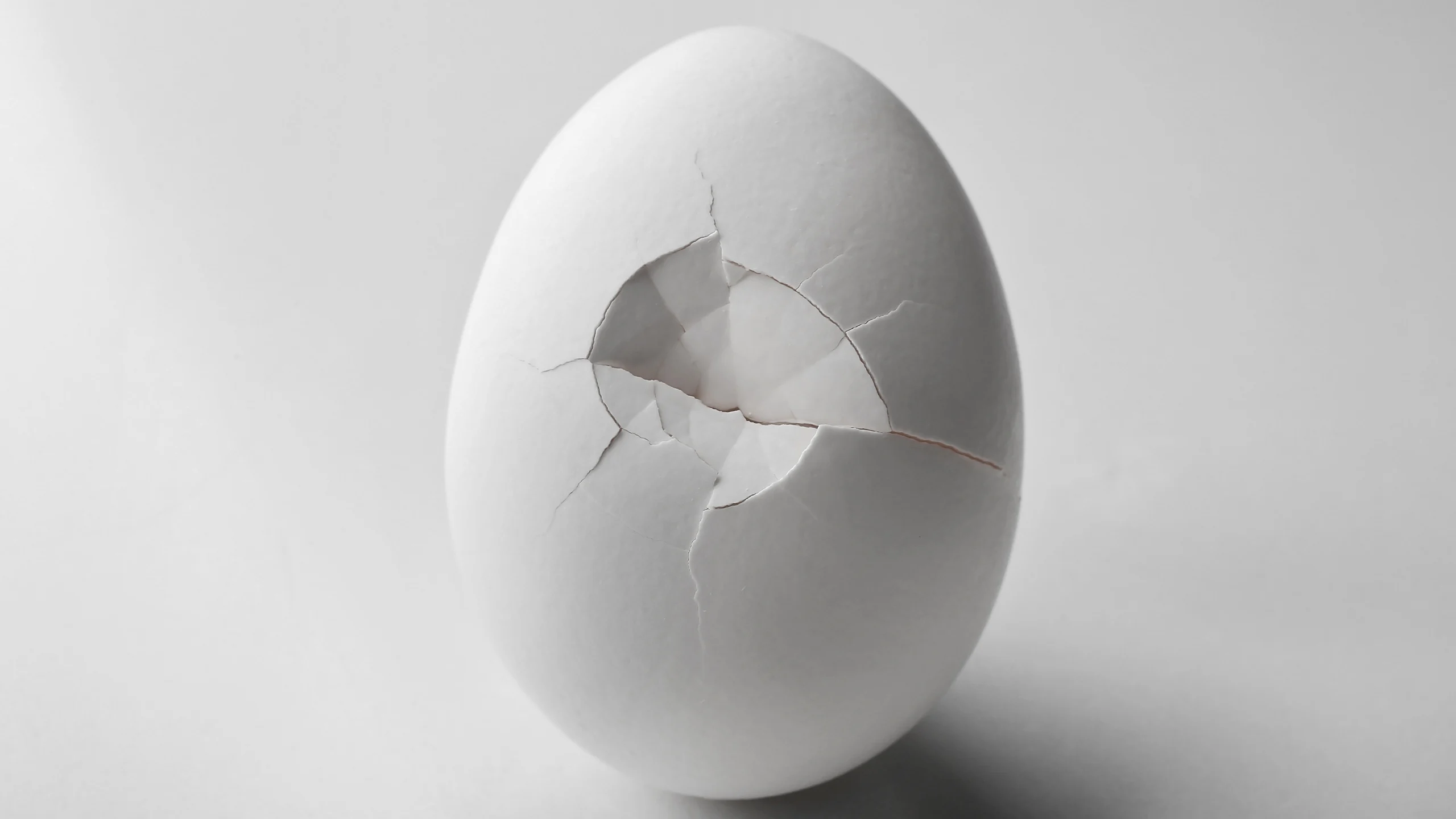 A cracked white egg on a white background.