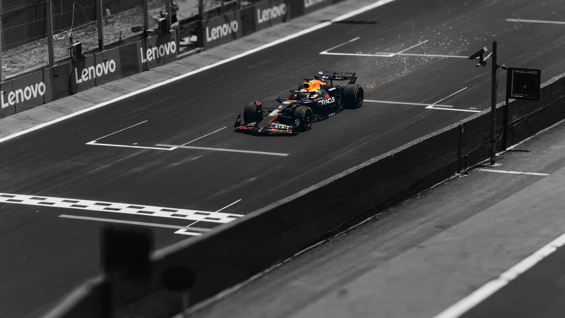 A Formula 1 racing car crosses the finish line. The background is black and white, but the car is in full colour.