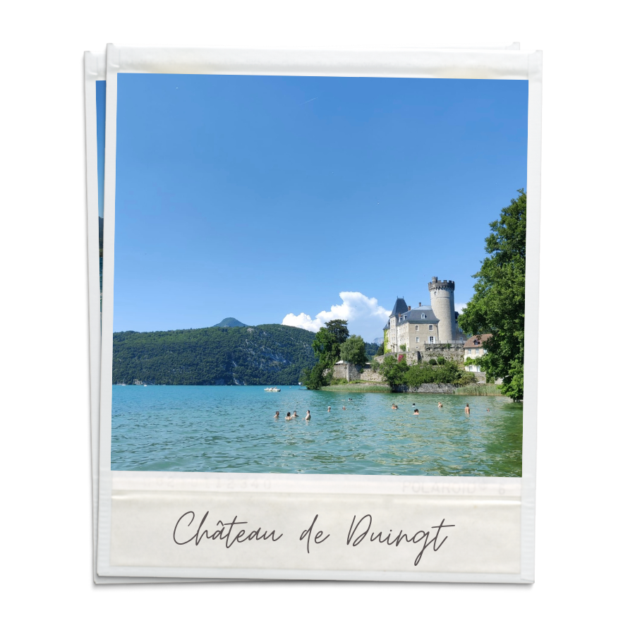 A polaroid of Château de Duingt. People are swimming in the clear lake next to the castle.