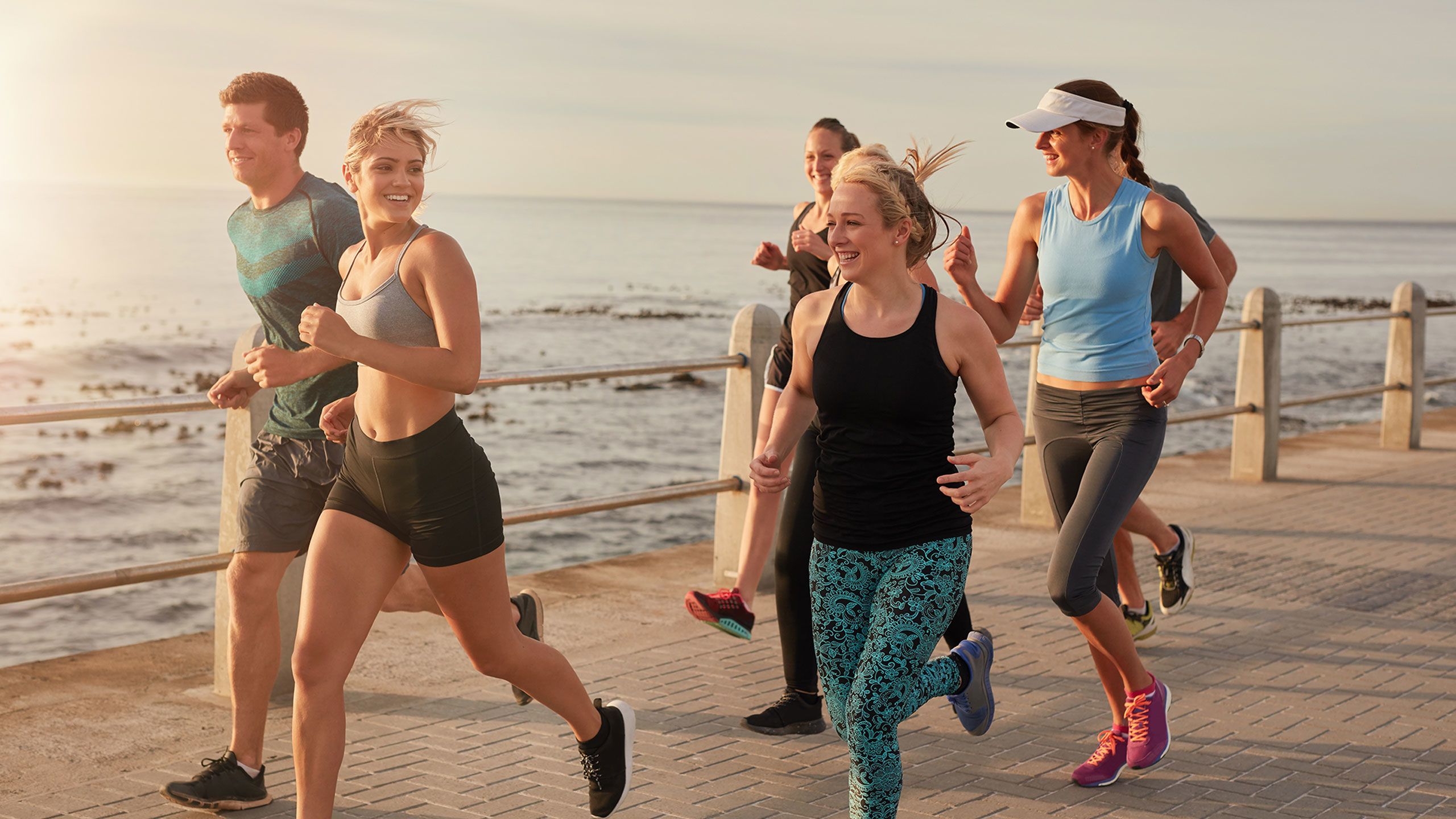 A group of men and women running together along the beach.