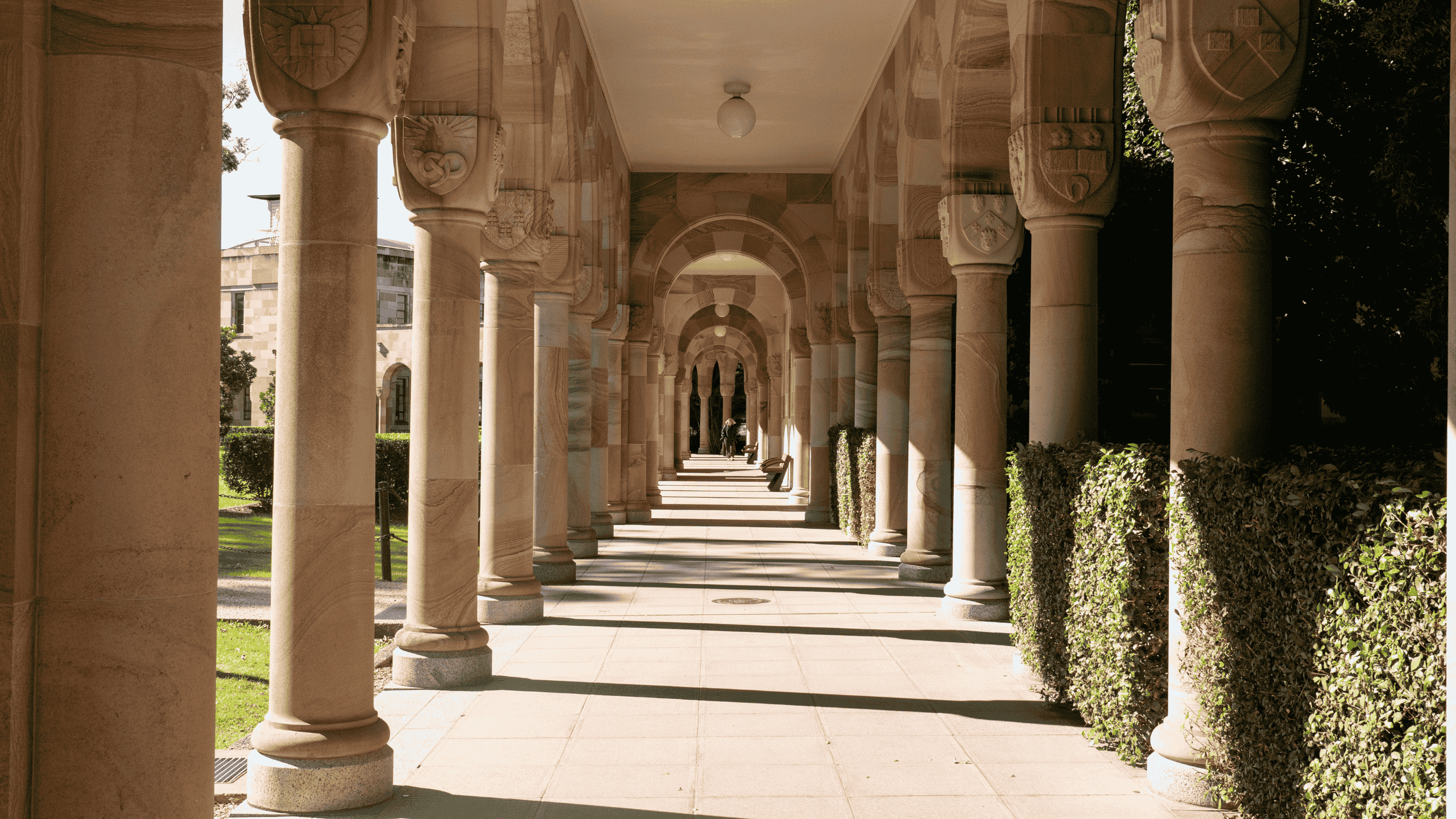 The image features the hallway of the Great Court, centred in between the sandstone cloisters.