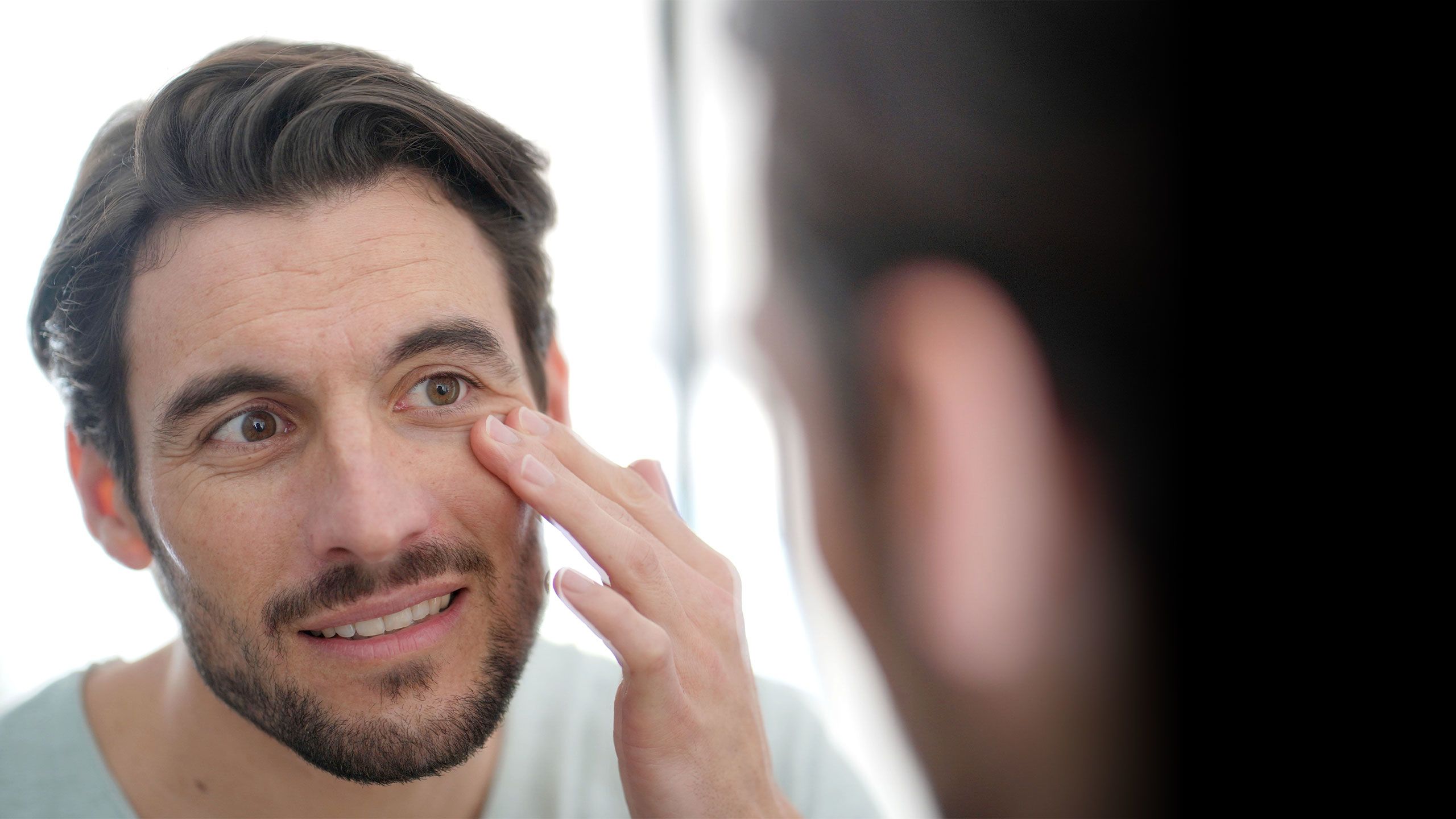 Man looking in the mirror at his wrinkles.